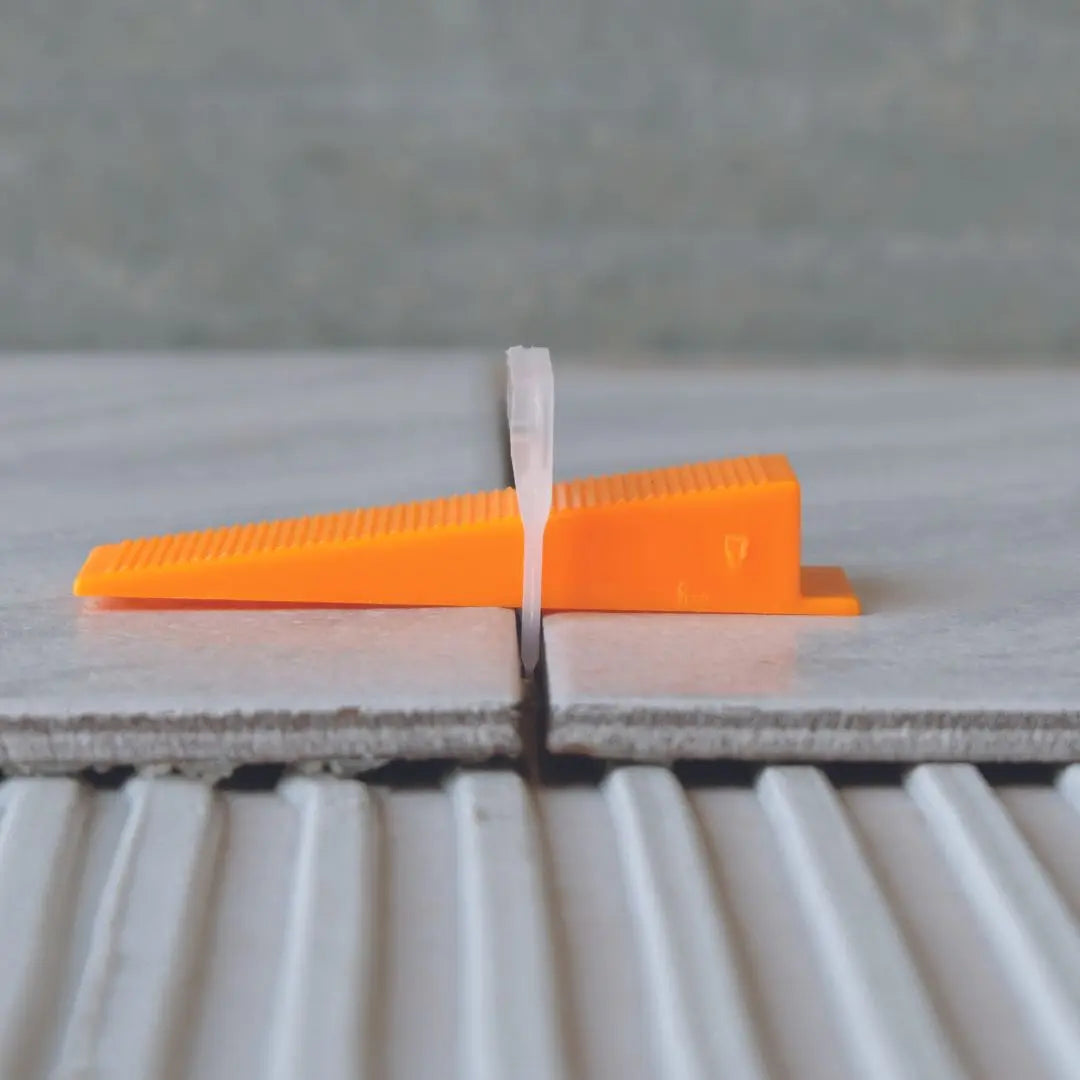 Levelit nivelleerclip en nivelleerspie tussen 2 tegels.