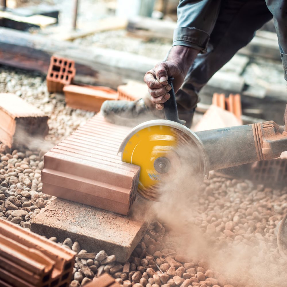 Sfeerfoto van man dat baksteen aan het slijpen is met slijpschijf.